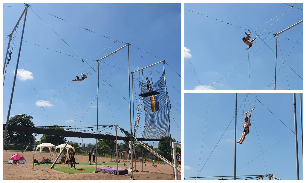 Sophie swinging high on a trapeze against a bright blue sky